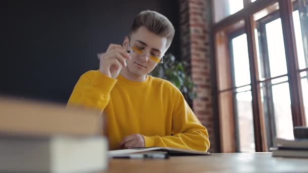 Jóvenes estudiantes pensando y escribiendo en cuaderno — Vídeos de Stock