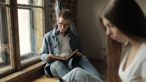 Jóvenes estudiantes leyendo libro y usando smartphone — Vídeo de stock