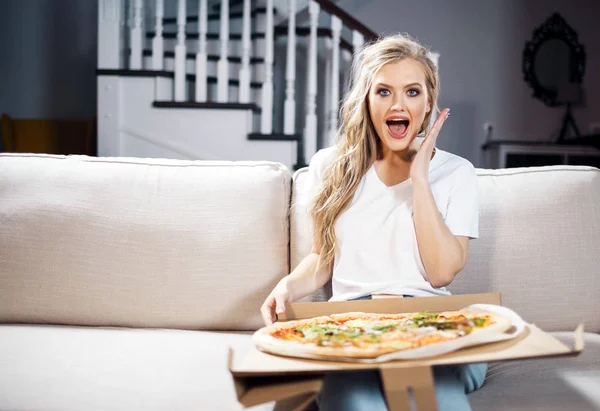 Žena jíst pizzu na pohovce — Stock fotografie