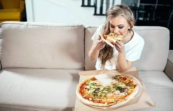 Mujer comiendo pizza en el sofá — Foto de Stock