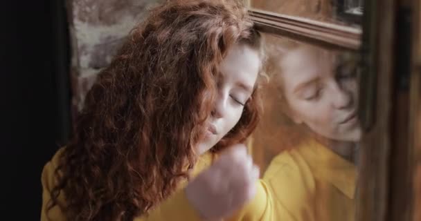 Šťastná dívka vlasy bruneta vyhlíží z okna — Stock video