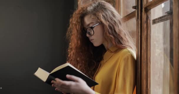 Joven chica bonita pensando y leyendo el libro — Vídeo de stock