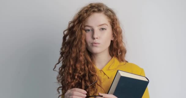 Jovem estudante posando com livro e óculos — Vídeo de Stock