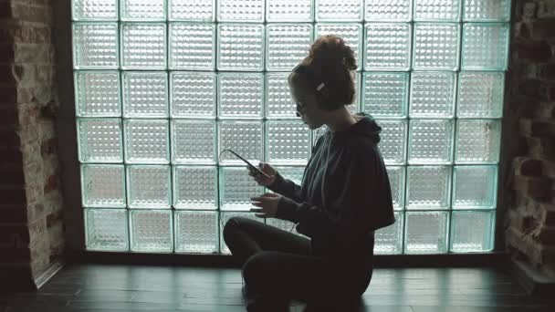 Fiatal lány ült a földön, és zenét hallgatni — Stock videók