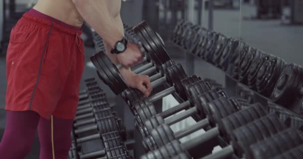 Człowiek wybiera Dumbbells na szafie — Wideo stockowe