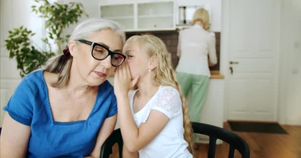 Petite-fille chuchotant à mamie à l'intérieur — Video