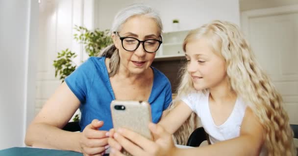 祖母和孙女滚动智能手机 — 图库视频影像