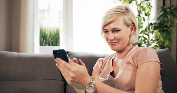 Žena s smartphone sedí na pohovce — Stock video