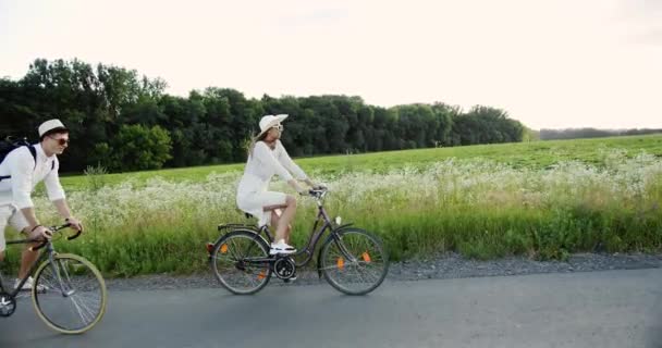 Pareja joven montando bicicletas en el campo — Vídeo de stock