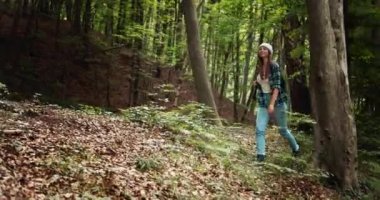 Sırt çantalı bir kadın ormanda yürüyüş yapıyor.