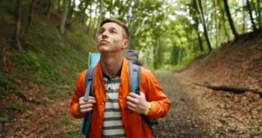 Sırt çantalı bir adam ormanda yürüyor.