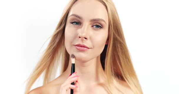 Mujer rubia aplicando maquillaje cepillo aislado — Vídeo de stock