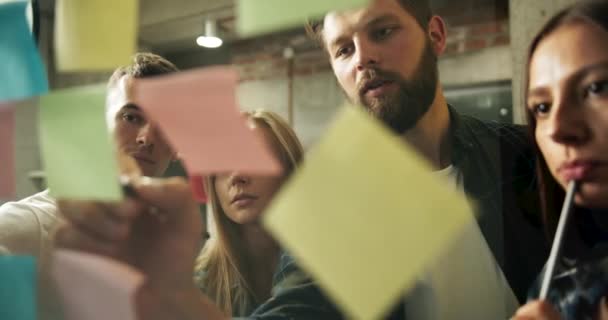 Team putting stickers op glazen wand brainstormen — Stockvideo