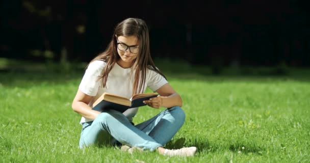 Frau liest Buch im Park — Stockvideo