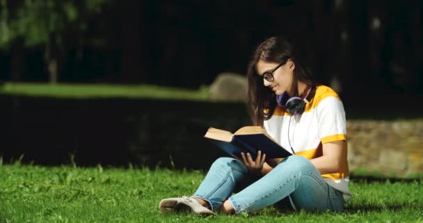 Kvinna läser bok i parken — Stockvideo