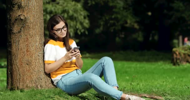 Mujer navegando Smartphone en Park — Vídeos de Stock