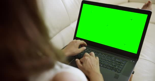 ソファにラップトップクロマキーを持つ女性 — ストック動画