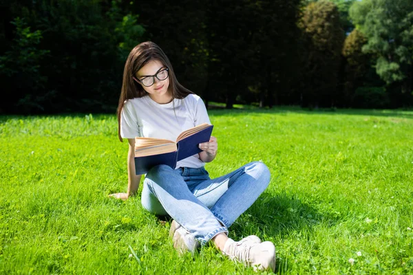 Gülümseyen Kız Çimenlikte Okumaktan Hoşlanıyor — Stok fotoğraf