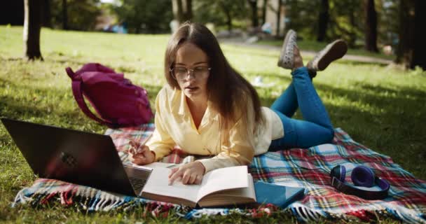 Estudiante femenina estudiando en el parque al atardecer — Vídeos de Stock