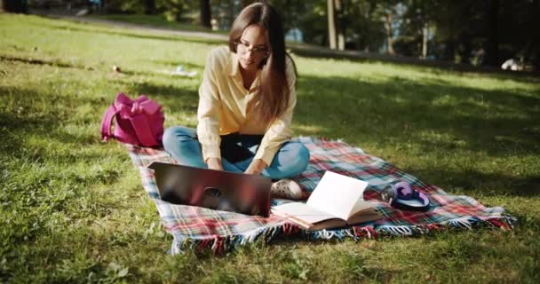 Студентка навчається в парку на заході сонця — стокове відео