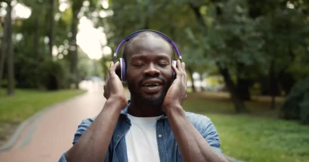 Afro-americano masculino em fones de ouvido cantando no parque — Vídeo de Stock