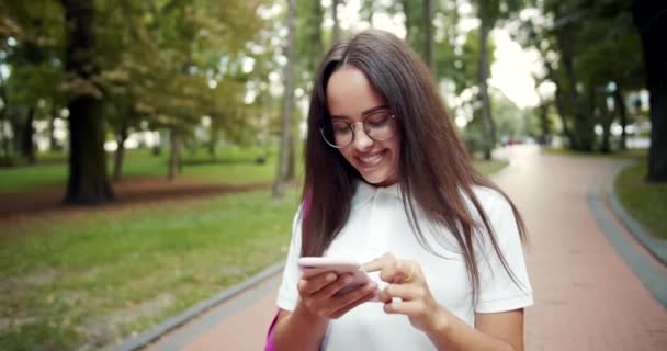 Κορίτσι περπάτημα και κύλιση smartphone — Αρχείο Βίντεο