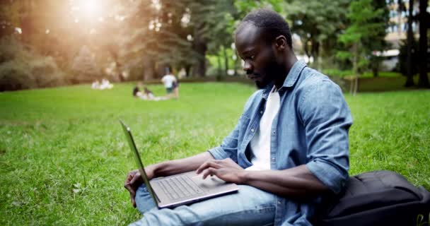 Estudiante africano con portátil en la puesta del sol del césped — Vídeos de Stock