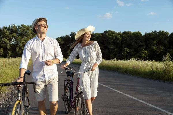 Young Couple Wheeling Bicycles Along Rural Road