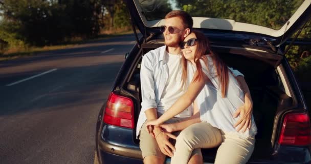 Щаслива пара сидить в машині на заході сонця — стокове відео