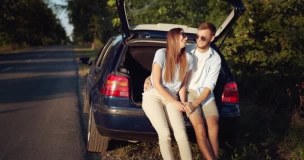 Пара сидящих в багажнике и расслабляющих — стоковое видео