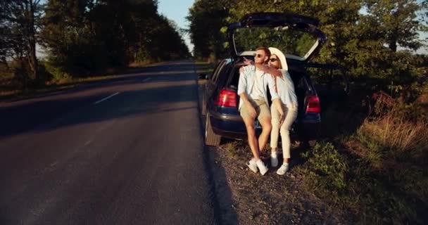 Casal sentado no carro tronco no por do sol — Vídeo de Stock