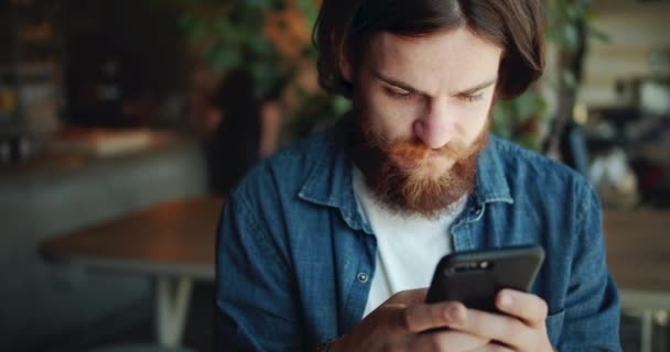 Тексты хиппи на смартфоне в кафе — стоковое видео