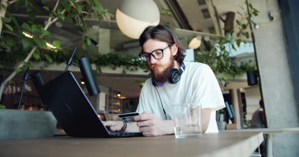 El hombre que paga con tarjeta de crédito en el ordenador portátil en Café — Vídeos de Stock