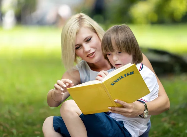 Uitgedaagd jongen geamuseerd door een boek — Stockfoto