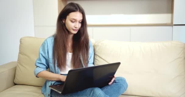 Νεαρή κυρία πληκτρολογώντας στο φορητό υπολογιστή σε κενό επίπεδο — Αρχείο Βίντεο