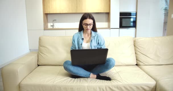 Joven dama escribiendo en el ordenador portátil en vacío plana — Vídeos de Stock