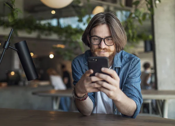 Homem jovem barbudo usando Smartphone — Fotografia de Stock