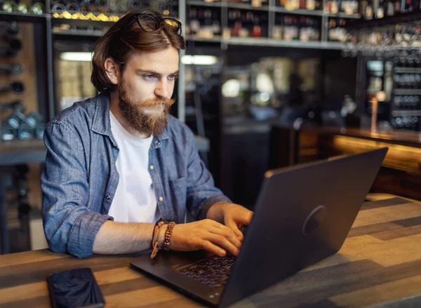 Молода людина використовує ноутбук у лофт-кафе — стокове фото