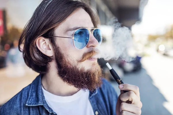 Youngster With Beard Smoking E-cigarette Outdoors