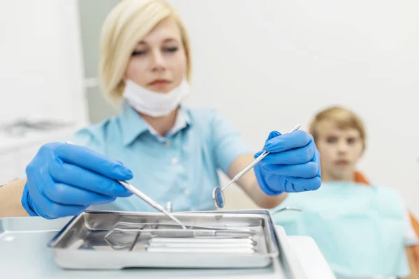 Женщина-стоматолог выбирает стоматологические инструменты — стоковое фото