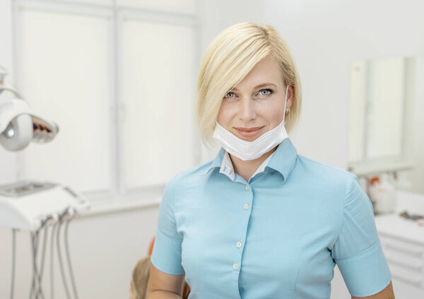 Beautiful Blonde Dentist in Blue Scrubs and Mask