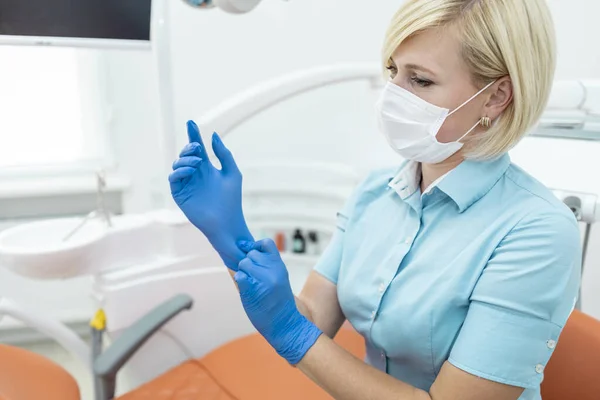 Loira dentista feminina ajustando luvas médicas — Fotografia de Stock
