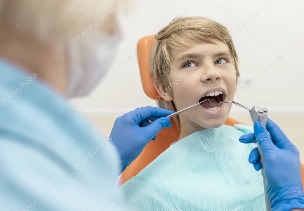 Boy With Water Spray Syringe and Dentist Probe in Mouth