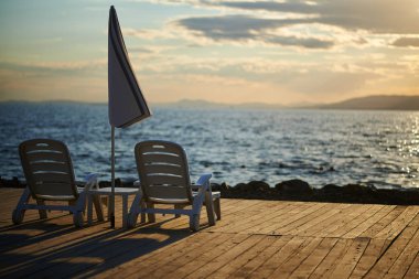 Gün batımında iskelede plaj sandalyeleri 