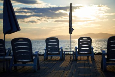 Gün batımında iskelede plaj sandalyeleri 