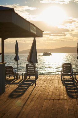 Gün batımında iskelede plaj sandalyeleri 