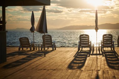 Gün batımında iskelede plaj sandalyeleri 
