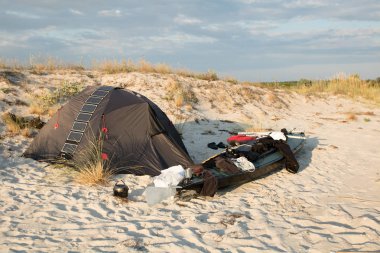güneş paneli ile çadır yakınındaki üst kayık. Deniz kum sahili. Günbatımı zamanı