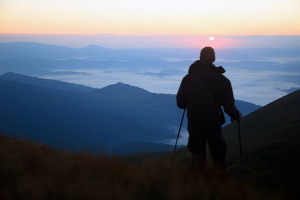 unrecognizable hiker male meets the dawn on the top of the mountain. sun rise time