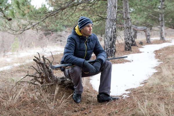 散弾銃で冬の森に白人の男が座っています 散弾銃で狩猟 — ストック写真